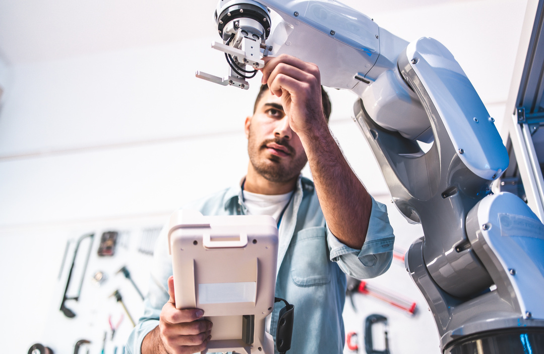 Male Engineer Checking Robotic Arm in Laboratory